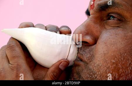 Hindu Priest soufflant la coquille de conch Banque D'Images