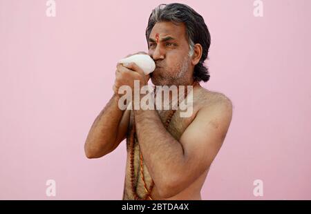 Hindu Priest soufflant la coquille de conch Banque D'Images