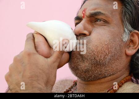 Hindu Priest soufflant la coquille de conch Banque D'Images