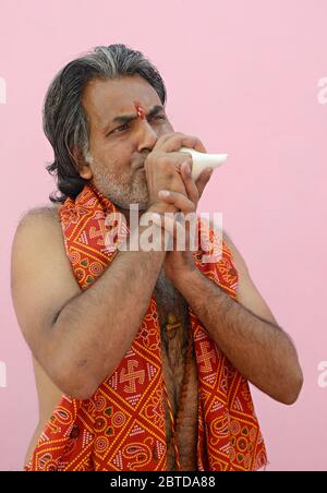 Hindu Priest soufflant la coquille de conch Banque D'Images