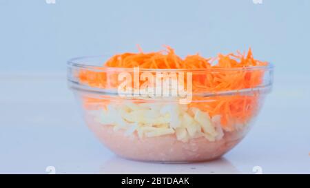 La fille prépare de la viande hachée. La main féminine ajoute des carottes, des oignons à la viande hachée et mélange. Plats à base de viande Banque D'Images