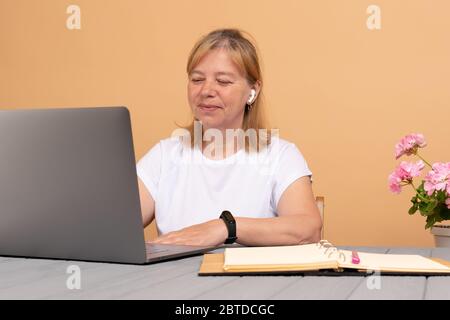 Tête de tir agréable heureuse femme d'âge moyen freelance travaillant sur ordinateur à la maison Banque D'Images