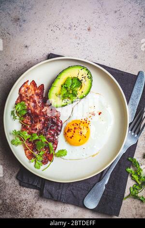 Keto breakfast - œuf frit, avocat et bacon dans une assiette blanche. Concept de régime de céto. Banque D'Images