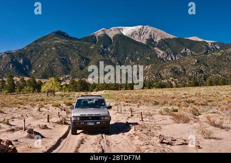 Véhicule 4WD à Medano Pass Primitive Road, montagnes Sangre de Cristo à distance, parc national de Great Sand Dunes, Colorado, États-Unis Banque D'Images