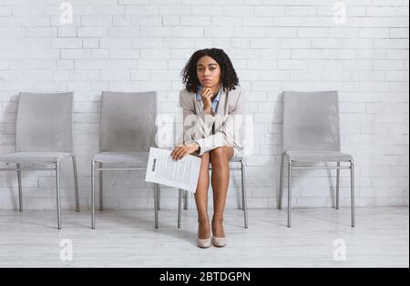 Jeune femme fatiguée avec CV en attente d'une entrevue de dépistage dans le hall du bureau. Copier l'espace Banque D'Images