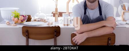 Joyeux jeune homme portant un tablier se préparant à cuisiner dans la cuisine à la maison, chef avec cuisine, restaurant et fier, la vie domestique, portrait de homme joyeux Banque D'Images