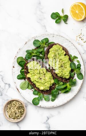 Pain de seigle vegan grillé avec purée d'avocat sur l'assiette, vue du dessus Banque D'Images