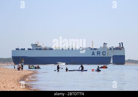 Southampton, Hampshire, Royaume-Uni. 25 mai 2020. Météo Royaume-Uni. Un transporteur de voitures passe devant les amateurs de plage de Calshot Beach en route vers les quais de Southampton. Credit Stuart Martin/Alay Live News Banque D'Images