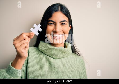 Jeune femme hispanique, belle pièce de puzzle comme solution de coopération dans les affaires avec un visage heureux debout et souriant avec un sourire confiant Banque D'Images