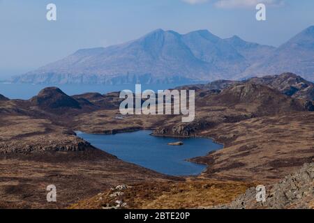 Un loch en forme de cœur juste en dessous du sommet d'Ann Sgurr sur Eigg, avec les montagnes de Rum en arrière-plan. Banque D'Images