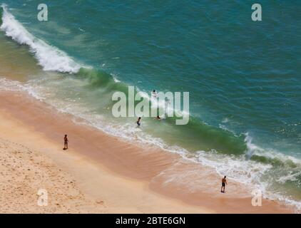 Nazaré, province de Leiria, Portugal. Mer agitée. De grandes vagues se brisent sur la rive. Les nageurs essaient de surfer sur le corps. Banque D'Images