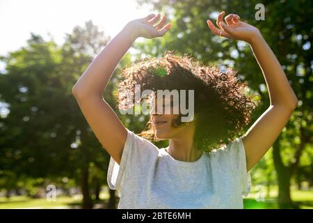 Femme insouciante dansant dans un parc pendant un après-midi ensoleillé Banque D'Images