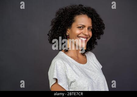 Jeune femme souriant debout sur fond gris Banque D'Images