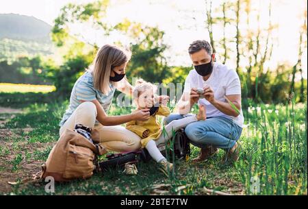 Famille avec petite fille en voyage cycliste, portant des masques faciaux. Banque D'Images