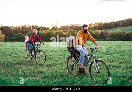 Famille avec deux petits enfants en voyage cycliste, portant des masques faciaux. Banque D'Images