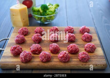 Boulettes de brut sur une planche à découper et ingrédients. Vue de dessus. Banque D'Images