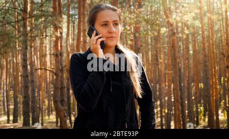 Portrait de la jeune randonneur de sexe féminin parlant au téléphone tout en randonnée en forêt Banque D'Images