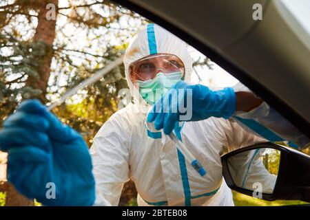 Confinement Scout du département de santé tient un frottis pour un test rapide du virus corona dans une station d'essai au volant Banque D'Images