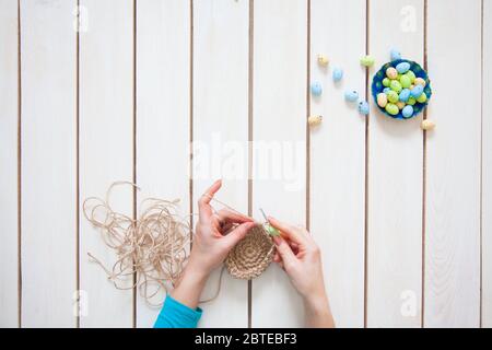 Une femme fait un nid pour les oeufs de Pâques. Lapin de Pâques. Fond blanc. Un jouet fait main. Banque D'Images