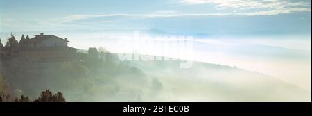 Italie. Toscane. Ancienne résidence sur une colline avec brume dans la vallée. Banque D'Images