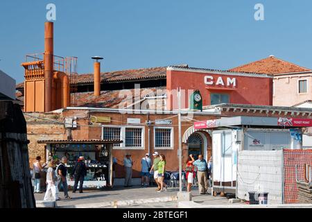 21 sept 2011: Ancienne cheminée de l'usine de verre CAM peint en rouge, partie de l'usine industrielle. Un stand vendant des bijoux en verre et des souvenirs sur Murano W. Banque D'Images