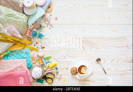 De nombreux matériaux arc-en-ciel différents pour la couture et la couture. Une fille / femme boit du thé. Banque D'Images