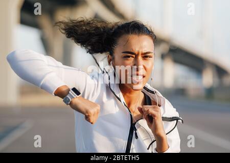 Forte jeune femme pratiquant la boxe à l'extérieur. Boxer féminin effectuant des poinçons. Banque D'Images