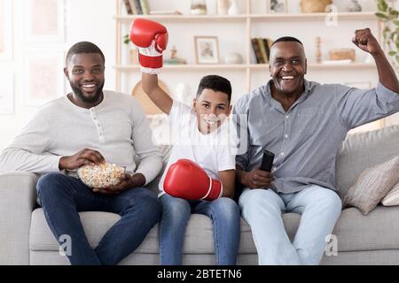 Activités familiales hommes. Père, fils et grand-père regardant la boxe se battre à la maison Banque D'Images