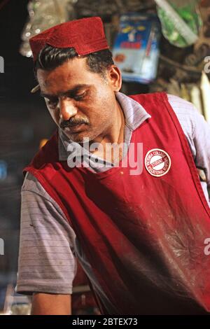 Vendeur portant le chapeau sindhi vendant un haar à sadar bazar karachi, Pakistan 15/03/2013 Banque D'Images