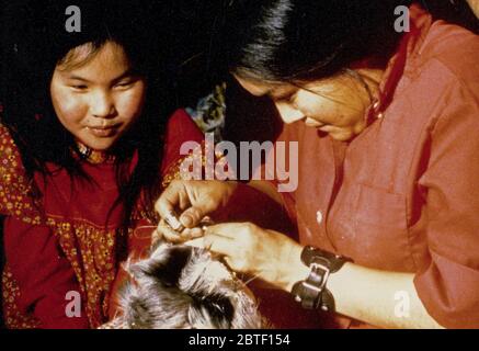 Mars 1974 - Au village de Ambler, un Esquimau femme enseigne une jeune fille l'art de la peau de caribou à coudre dans l'hiver des mukluks Banque D'Images