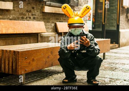 Un employé de Meituan Dianping se croche en utilisant son téléphone en attendant son prochain emploi dans le quartier branché de Xintiandi à Shanghai. Banque D'Images