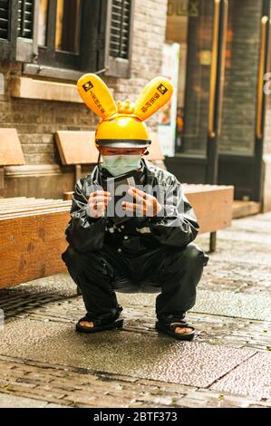 Un employé de Meituan Dianping se croche en utilisant son téléphone en attendant son prochain emploi dans le quartier branché de Xintiandi à Shanghai. Banque D'Images