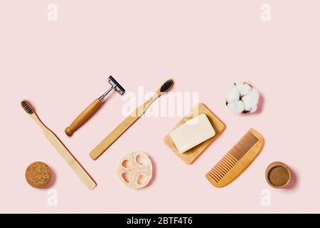 Accessoires de salle de bains sur fond rose. Brosse à dents en bambou naturel, éponges, fleurs en coton, brosse à rasage. Flat lay, vue de dessus. Banque D'Images