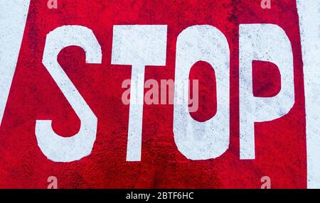 Signal d'arrêt peint sur l'asphalte rouge d'une route. Banque D'Images