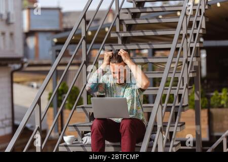 Fou choqué. Jeune homme, homme d'affaires travaillant à l'extérieur concentré, regardant sur l'écran d'ordinateur portable. CopySpace pour votre annonce. Finance, affaires, travail, gadgets et concept technologique. Freelance, travailleur à distance. Banque D'Images