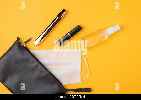 Masque et désinfectant pour les mains comme partie normale de la vie quotidienne concept. Vue du dessus de la tête à plat photo d'un masque de sac cosmétique bouteille d'assainisseur pour les mains en t Banque D'Images