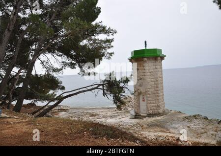 Phare sur la petite île entourée de pins Banque D'Images