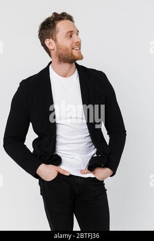 Image d'un homme en veste satisfait et sans être rasé, souriant et regardant de côté, isolé sur fond blanc Banque D'Images