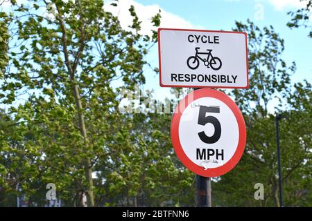 British cycle Responsibly signez indiquant la limite de vitesse de cinq miles par heure dans un parc les citoyens se connectent en vélo ou apprécient de se promener tranquillement dans la ville Banque D'Images