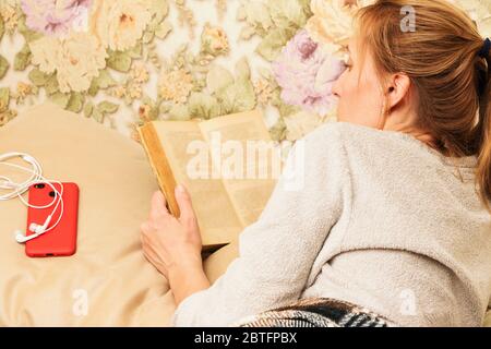 Une jeune femme lit un livre au lit. Banque D'Images