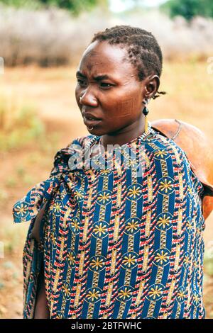 Tribu TOPOSA, SOUDAN DU SUD - 12 MARS 2020 : femme enveloppée de vêtements décoratifs colorés, en regardant loin dans le champ près de la tribu Toposa Banque D'Images
