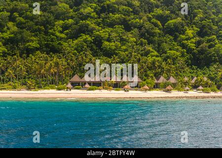 Bungalows sur la plage de sable blanc avec une forêt tropicale en arrière-plan. L'eau de la Turuqoise au premier plan. Banque D'Images
