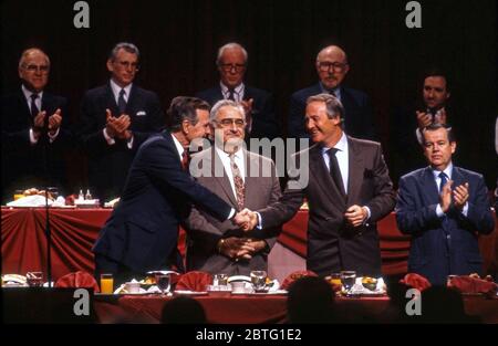 Le président George Bush se serre la main avec Jerry Weintraub après avoir pris la parole devant des membres de l'Académie des arts et des sciences de la télévision à Los Angeles, vers les années 1990 Banque D'Images