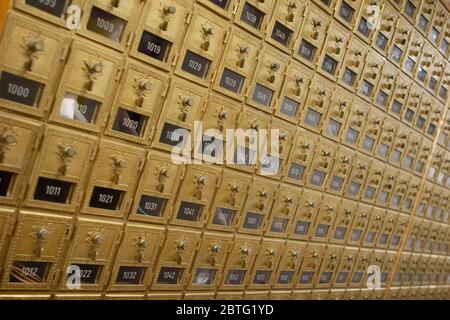 Rangée de boîtes aux lettres en laiton d'époque avec portes et serrures combinées dans une salle de courrier. Banque D'Images