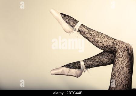 Belle femme danseuse de ballet, partie de corps jambes dans les chaussures et les collants dentelle noir sur fond gris, studio shot Banque D'Images