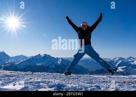 Fille avec des lunettes et un casque est en plein air en hiver. Ciel bleu et soleil éclatant au sommet des montagnes en Suisse. Concept. Banque D'Images