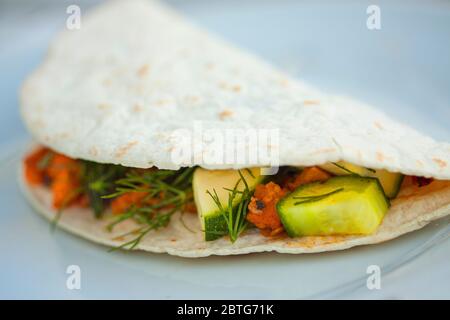 Tortilla végétalienne maison avec haricots noirs, concombre, courge, poivrons, patates douces, purée d'avocat et aneth. Image de gros plan extrême avec sele Banque D'Images