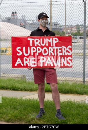 Baltimore, Maryland, États-Unis. 25 mai 2020. Homme avec masque facial protecteur tient le signe lisant « les partisans de Trump sont des pions » à l'extérieur de l'historique fort McHenry à Baltimore, Maryland, Où le président Donald Trump et la première dame Melania Trump visitent le Memorial Day 2020 malgré l'insistance du maire de Baltimore Bernard C. « Jack » Young à annuler pour éviter de donner un mauvais exemple alors que la ville reste en ordre de rester à la maison (avec des exemptions incluant un exercice de plein air), et éviter de faire des dépenses coûteuses en ressources de sécurité publique. Kay Howell/Alay Live News Banque D'Images