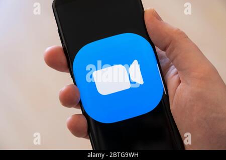 Main d'un homme (39 ans) tenant un smartphone avec un grand logo pour l'application d'appel vidéo Zoom Banque D'Images