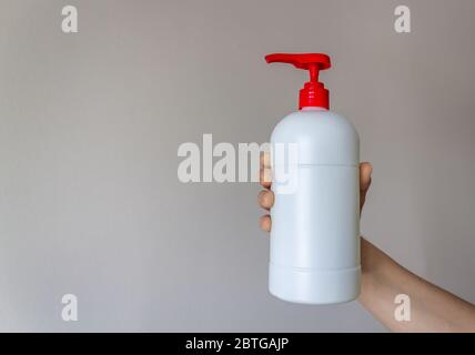 Bouteille de pompe en plastique blanc isolée sur fond blanc, la femme tient une bouteille en plastique dans sa main. Zone de texte publicitaire de l'espace de copie Banque D'Images